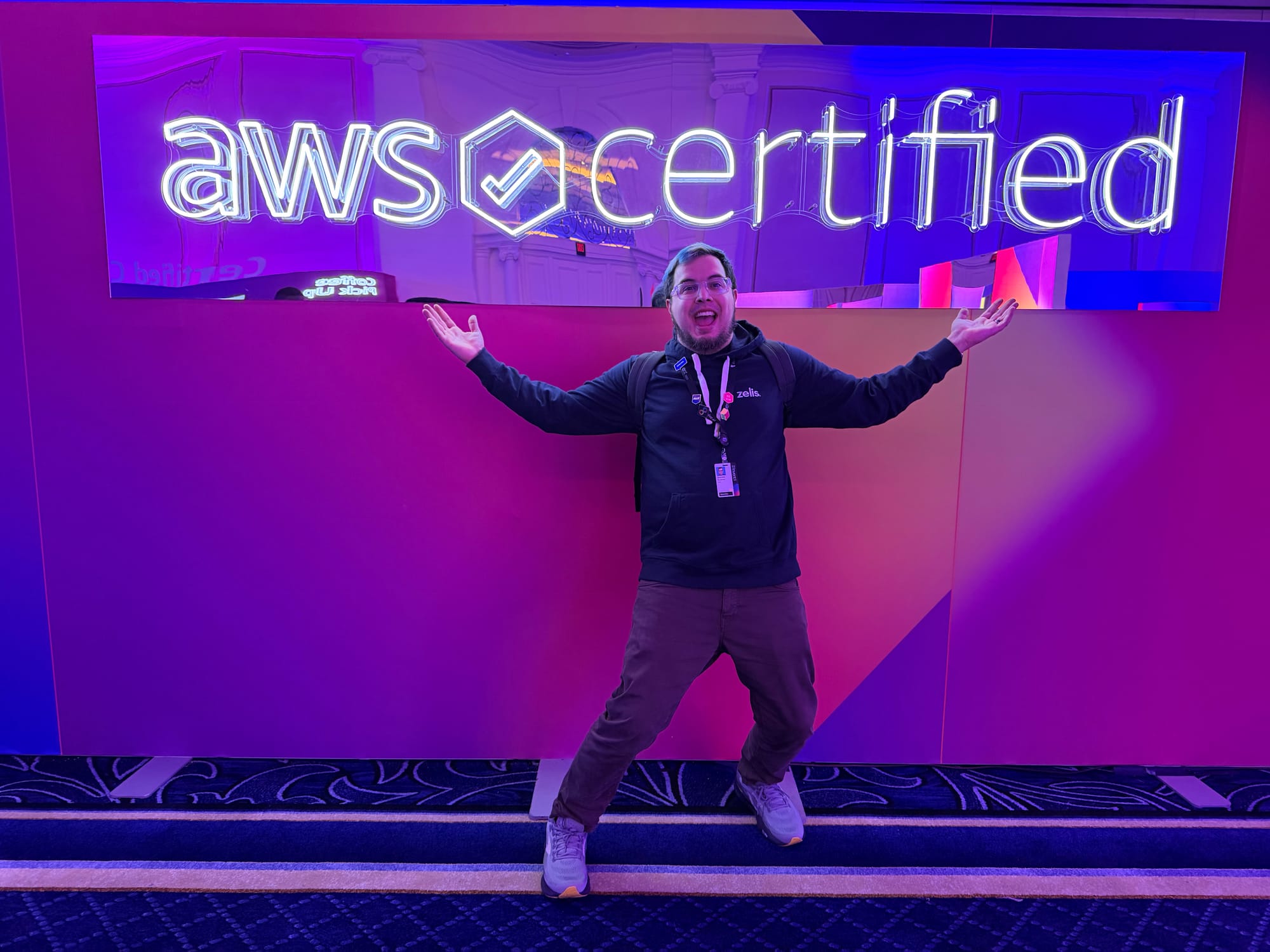 Picture of a person in front of a sign saying AWS Certified